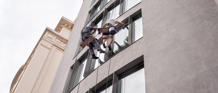 Two workers washing windows outside a modern building